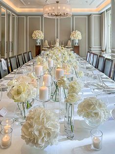 a long table is set with white flowers and candles