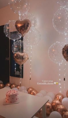 some balloons are hanging from the ceiling near a table with a cake and cupcake on it