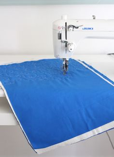 a sewing machine is on top of a blue table cloth that has been sewn