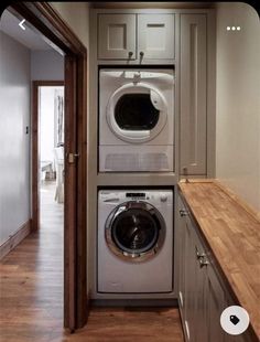 a washer and dryer in a small room with wood flooring on the side