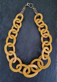 "Oversized chunky chain link necklace entirely handmade link by link from polymer clay in mustard dark yellow shade, finished with gold plated chain (can be finished with other chains too, see options). Unique yet versatile modern statement necklace that is sure to elevate any outfit. ►Length: 18 to 32 inches and extender for extra 2\"  (46 to 81cm+5cm). Pick your length from the drop down menu!  Lobster clasp closure on the back. ►► Modeled necklace on the pictures is 22 inches long ►Need this in different color: Send me a message! ►Your necklace comes beautifully gift wrapped and ships within 3-5 days of purchase. ►More colorful necklaces in different colors see here:  https://www.etsy.com/shop/AlinaandT?section_id=6873674&ref=shopsection_leftnav_9 ►See my shop announcement section for c Modern Yellow Gold Chunky Chain Necklace, Bold Chunky Gold Necklace, Trendy Gold Resin Necklace, Bold Gold Chunky Necklace, Yellow Gold Chunky Chain Choker Necklace, Artisan Yellow Necklace With Large Beads, Artistic Handmade Yellow Necklace, Unique Yellow Necklace With Large Pendant, Chunky Statement Necklace