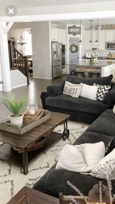 a living room filled with black couches and white pillows