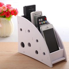 a cell phone holder with two phones in it sitting on a table next to a vase