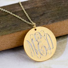 a gold plated necklace with the word go and m on it sitting on a wooden surface