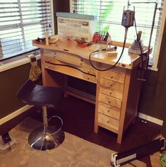 a desk and chair in a room with blinds on the window sill, next to a lamp