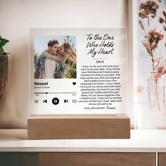 a wooden block with a photo on it next to a potted plant and a vase