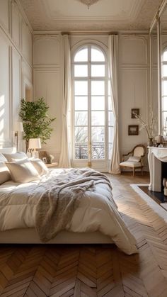 a bed sitting in a bedroom next to two windows and a table with a potted plant on it