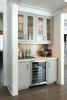 a kitchen with white cabinets and wood floors