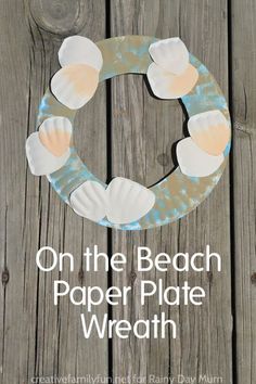 a paper plate wreath with seashells on it and the words, on the beach paper plate wreath