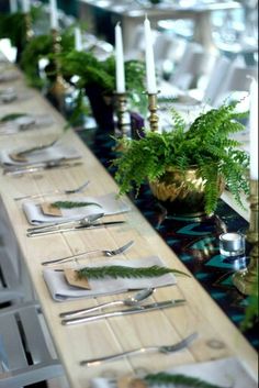 the table is set with silverware and greenery