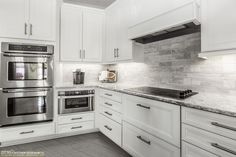 a kitchen with white cabinets and stainless steel appliances in the center, along with marble counter tops