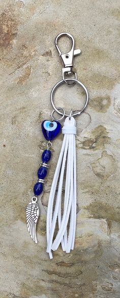 a white leather keychain with blue beads and an angel charm hanging from it