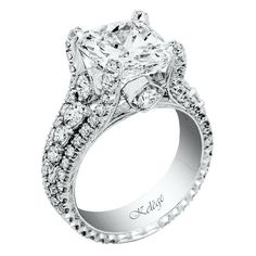 an engagement ring with a princess cut diamond surrounded by smaller round diamonds and pave set shoulders