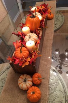 pumpkins and gourds are arranged on a burlocked table runner