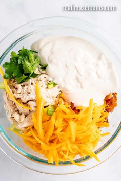 a glass bowl filled with chicken, cheese and sour cream