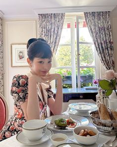 a woman sitting at a table with plates and bowls on it