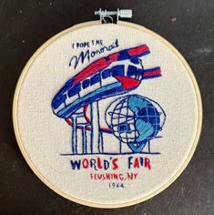 the embroidery on this hoop depicts an airplane and world's fair logo