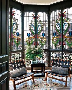 an image of a living room with stained glass windows on the wall and furniture in the middle