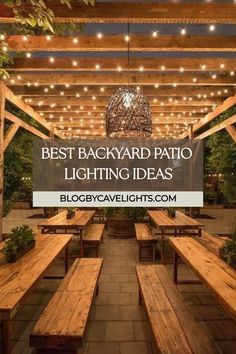 an outdoor patio with wooden benches and lights hanging from the ceiling, surrounded by greenery