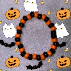 a bracelet made out of plastic beads with halloween decorations around it on a gray surface