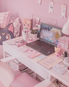 a laptop computer sitting on top of a white desk next to a pink chair and pillow