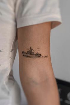 a small boat tattoo on the left arm