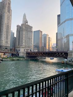 a bridge over a river with boats on it and tall buildings in the back ground