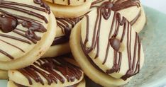 cookies with chocolate drizzled on them sitting on a blue plate next to a pink towel