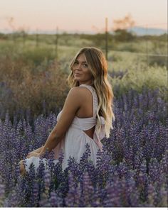 a woman standing in a field of purple flowers