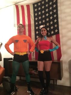 two people dressed in costumes standing next to each other near an american flag on the wall