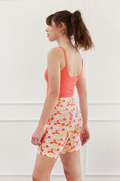 a woman walking down the street wearing shorts and a tank top with flowers on it