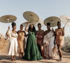 four women in dresses are holding umbrellas over their heads and posing for the camera