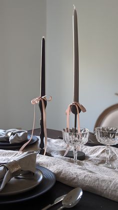 two candles are sitting on the table with plates and silverware in front of them