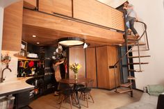 two people are climbing up the stairs in a loft apartment with wood paneling and metal railings