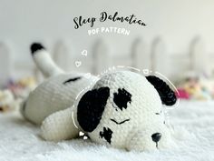 a white stuffed dog laying on top of a bed next to a toy animal with black spots