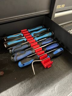 a bunch of tools are sitting in the back of a truck with red and blue handles