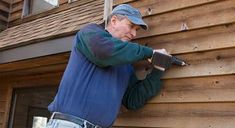 a man holding a hammer while standing next to a wooden building