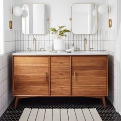 a bathroom vanity with two mirrors above it and a rug on the floor next to it