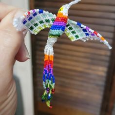 a hand holding a small colorful bird ornament