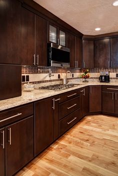 a large kitchen with wooden cabinets and marble counter tops, along with hardwood flooring