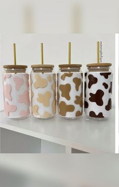 four jars with gold, pink, and brown dog prints are lined up on a table