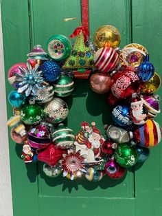 a wreath made out of christmas ornaments on a green door