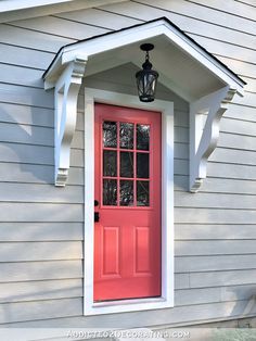 a red front door with white trim and a light on the side of a house