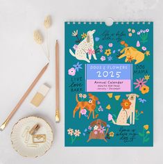 a notebook with dogs and flowers on it next to some pencils, paintbrushes and other items