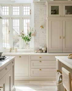 a kitchen filled with lots of white cabinets and counter top space next to a window