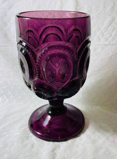 a purple glass cup sitting on top of a white table