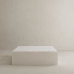 a white square object sitting on top of a floor in front of a gray wall