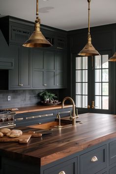 a large kitchen with wooden counter tops and hanging lights over the stove top, along with black cabinets