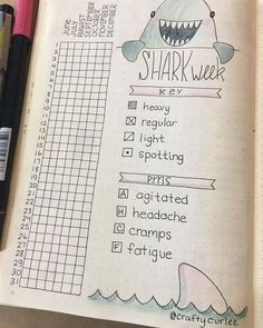 an open notebook with writing on it and a shark week chart in the middle next to some markers