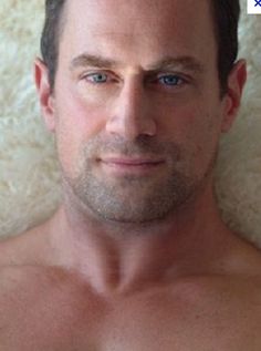 a shirtless man with blue eyes and no shirt is looking at the camera while posing for a photo